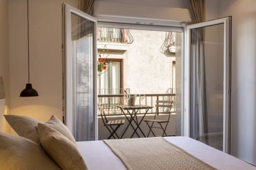 Dormitorio luminoso en Room Boutique 32 de Denia con puertas de balcón abiertas hacia el patio interior y zona de descanso