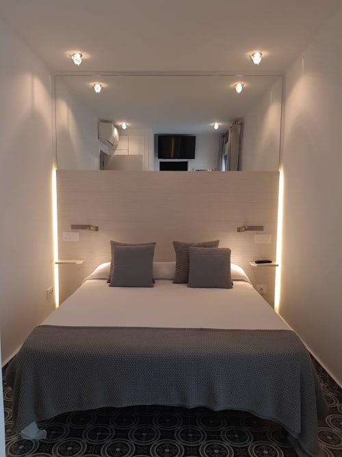Modern bedroom at Room Boutique 32 hostel in Denia with bed, ambient lighting, mirror, and TV