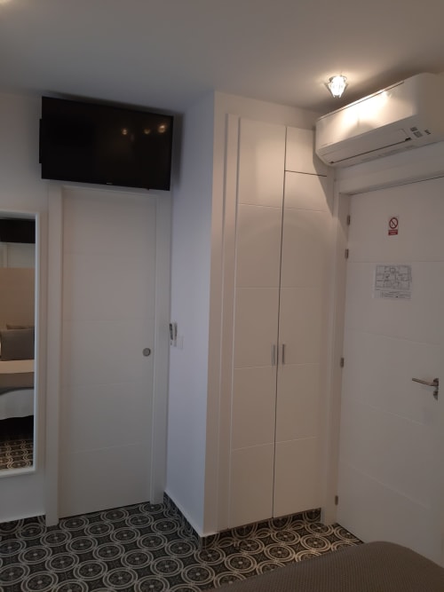 Habitación moderna del hostal Room Boutique 32 en Denia con TV montada en pared, aire acondicionado y suelos de azulejos con patrón