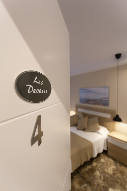 Room 4 entrance at Room Boutique 32 hostel in Denia with circular 'Les Deveses' sign and bedroom view