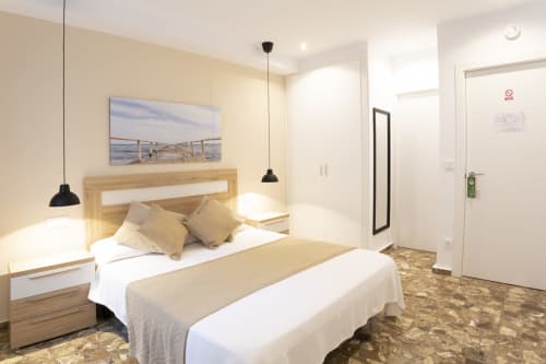 Dormitorio moderno en hostel Room Boutique 32 de Denia con cama queen, cabecero de madera, iluminación colgante y diseño contemporáneo