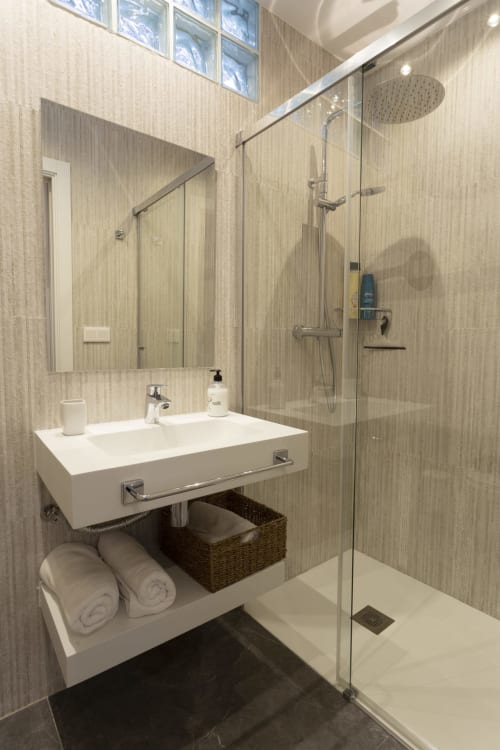 Baño moderno en Room Boutique 32 hostel en Denia con lavamanos blanco, ducha abierta y alcachofa de lluvia