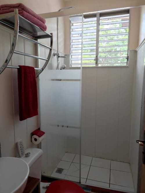 Salle de bain moderne à la Résidence Les 2 Moulins au Moule avec douche, toilettes et fenêtre à jalousies