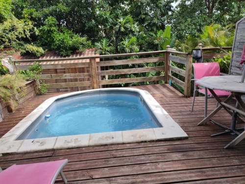 Bain à remous sur terrasse en bois entouré de plantes tropicales à la Résidence Les 2 Moulins, Guadeloupe