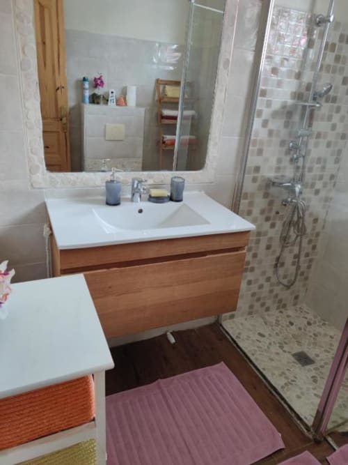 Salle de bain moderne avec meuble-lavabo en bois, lavabo blanc, miroir et douche à l'italienne aux Résidence Les 2 Moulins, Le Moule
