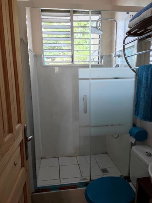 Salle de bains moderne avec douche à l'italienne, carrelage blanc et fenêtre donnant sur la verdure à Résidence Les 2 Moulins