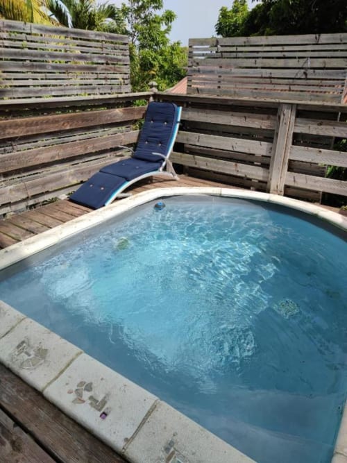 Bain à remous de la Résidence Les 2 Moulins au Moule, Guadeloupe, avec transat bleu et clôture en bois