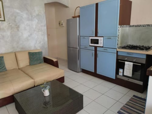 Cuisine studio moderne avec armoires bleues, appareils en acier inoxydable, canapé crème et carrelage
