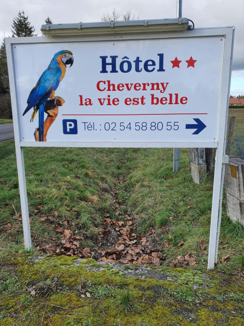 Panneau routier de l'Hôtel Cheverny La Vie Est Belle avec ara bleu, informations de stationnement et numéro de téléphone en France