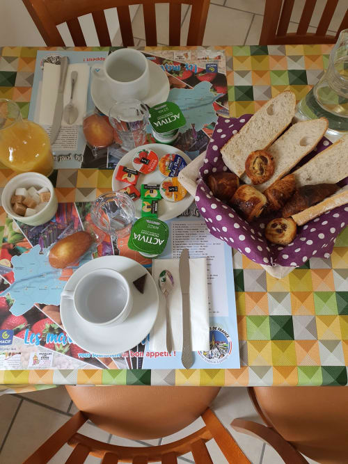 Petit-déjeuner copieux à l'Hôtel Cheverny La Vie Est Belle avec viennoiseries, pain, yaourt, confiture et café sur nappe géométrique