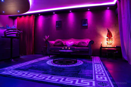 L'Insolite Spa Privatif, appartement privé à Toulouse avec éclairage néon violet, canapé luxueux et motifs géométriques