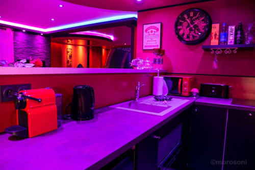 Appartement spa L'Insolite à Toulouse avec éclairage rose néon et violet vibrant, réception privée avec bureau