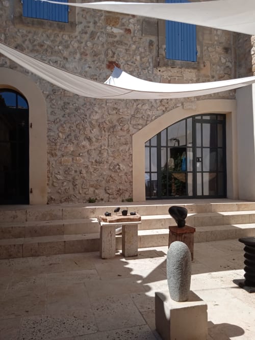 Courtyard at Mas des Artistes B&B in Mouriès with stone sculptures and white sail shade