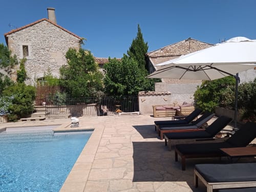 Mas des Artistes poolside in Mouriès with loungers, umbrella, and stone Provençal buildings