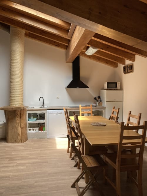 Amplia zona de cocina-comedor en apartamento Casa Lafuente con vigas de madera, mesa de comedor, electrodomésticos modernos y elementos expuestos