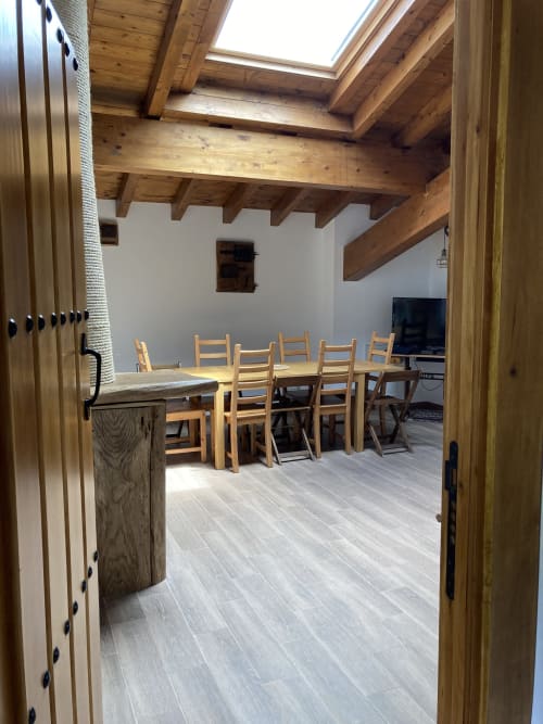 Amplia zona de estar y comedor abierta en Casa Lafuente con vigas de madera vista, mesa rústica y televisor