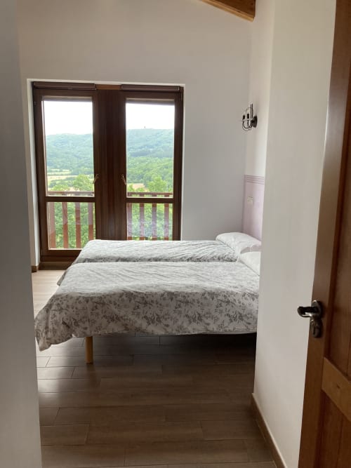 Dormitorio con dos camas y vistas a la montaña desde el balcón en Casa Lafuente, Lukiano