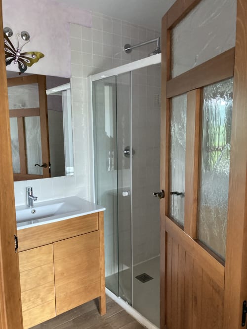 Baño moderno en Casa Lafuente con tocador de madera, lavabo blanco, ducha con cristal y paredes alicatadas