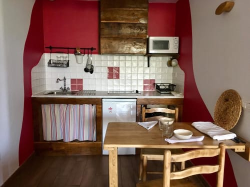 Cocina y comedor compactos en Casa Lafuente con paredes rojas, muebles de madera y salpicadero de azulejos blancos en Lukiano