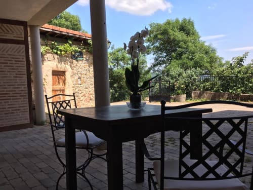 Patio cubierto del hotel Casa Lafuente en Lukiano con mesa de comedor negra, sillas y planta macetada con vista a las montañas verdes