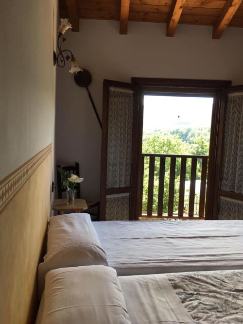 Dormitorio luminoso en Casa Lafuente con vistas a las montañas desde balcón de madera, vigas vistas y paisaje pastoral en Araba