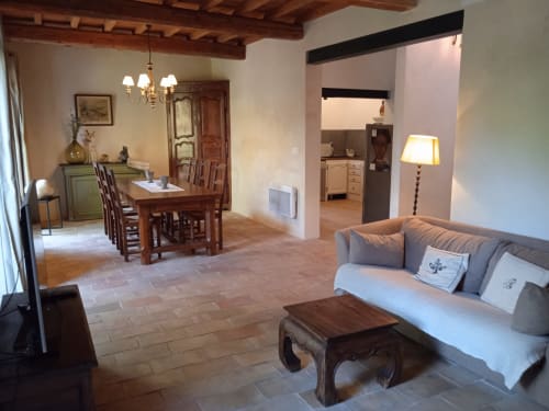 Spacious cottage living room with dining area, fireplace, beamed ceilings, and kitchen at Mas des Artistes in Mouriès
