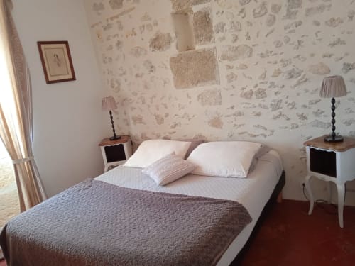 Cozy bedroom at Mas des Artistes cottage in Mouriès with floral wallpaper, double bed, white nightstands, and garden view