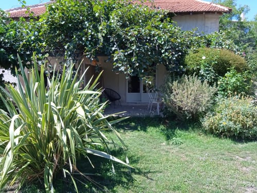 Vue du jardin de chaumière du Mas des Artistes à Mouriès avec terrasse, verdure luxuriante et espace de détente confortable