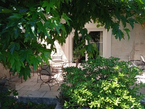 Shaded courtyard patio at Mas des Artistes B&B in Mouriès with lush green vines, potted plants, and wrought iron seating area