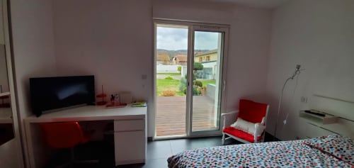Chambre moderne au Chez Anne Marie B&B à Beausemblant avec TV, bureau, accents rouges et vue sur le jardin