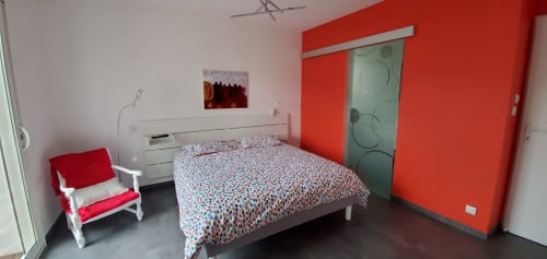 Chambre moderne au Chez Anne Marie B&B à Beausemblant aux murs rouges, lit patterné et mobilier blanc