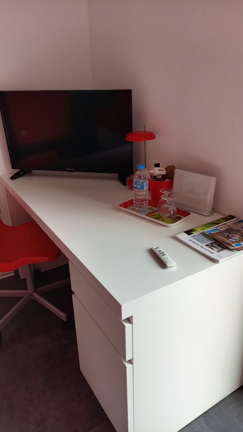 Espace de travail moderne au gîte Chez Anne Marie B&B à Beausemblant avec téléviseur, bouteille d'eau et chaise rouge