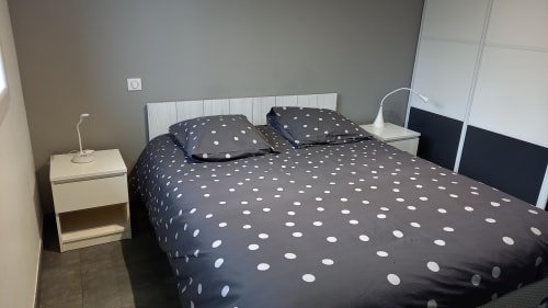 Chambre de Chez Anne Marie avec literie à pois, tête de lit blanche et vue sur le jardin à Beausemblant, France