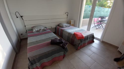 Chambre twin du gîte Chez Anne Marie avec literie rayée, portes donnant sur le jardin et équipements modernes à Beausemblant