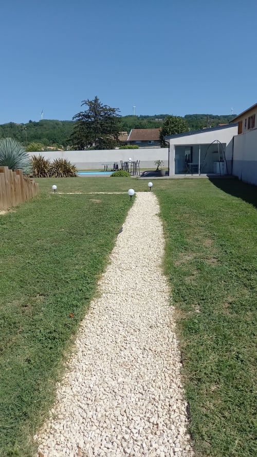 Jardin champêtre moderne avec allée de gravier et pelouse verdoyante à la Maison d'hôtes Chez Anne Marie à Beausemblant, France