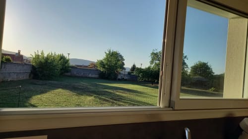 Vue du jardin du gîte Chez Anne Marie à Beausemblant, France, avec pelouse verdoyante et arbres environnants