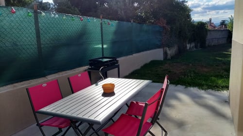 Terrasse extérieure avec chaises rouges et table au gîte Chez Anne Marie à Beausemblant, vue sur le jardin