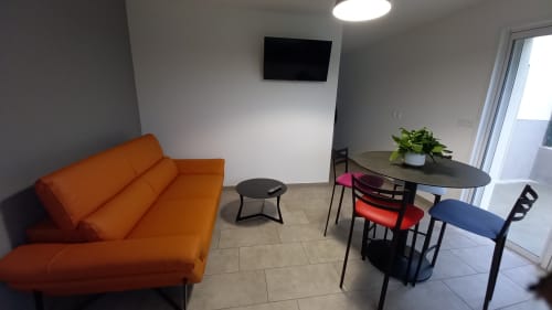 Espace salon contemporain du gîte Chez Anne Marie à Beausemblant avec canapé orange, table à manger et vue sur le jardin