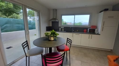 Cuisine et salle à manger modernes du gîte Chez Anne Marie à Beausemblant, table ronde, chaises colorées, vue sur le jardin