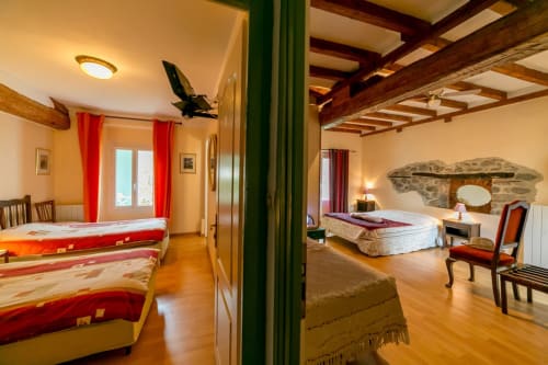 Spacieuse suite chambre aux 2 Lions à Vernet-les-Bains avec plusieurs lits, poutres bois et ambiance chaleureuse