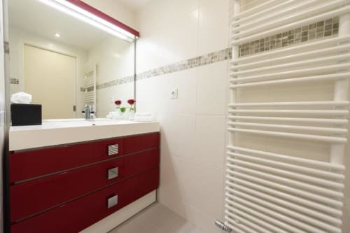 Modern bathroom with red vanity, white sink, large mirror, and heated towel rack at Clos Céleste Campagne d'Etretat,