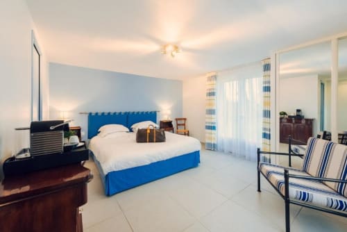 Spacious blue and white bedroom at Clos Céleste in Ecrainville with pool view, striped curtains, and modern amenities