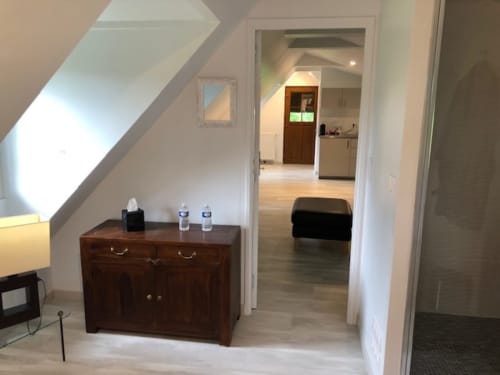 Bright attic room at Clos Céleste with wooden dresser, open-plan layout, and access to kitchen and sitting area