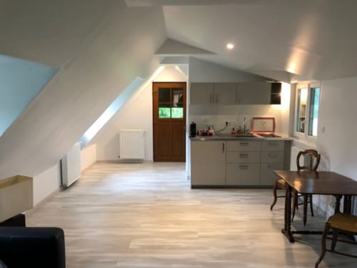 Modern attic suite at Clos Céleste with open-plan kitchen, dining area, and living space featuring sloped ceilings and