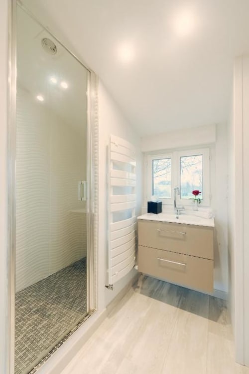 Modern bathroom with walk-in shower and vanity at Clos Céleste, Ecrainville. Windows overlook countryside views.