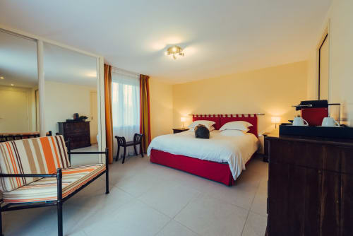 Spacious bedroom at Clos Céleste with red headboard, striped chair, and modern amenities in Ecrainville