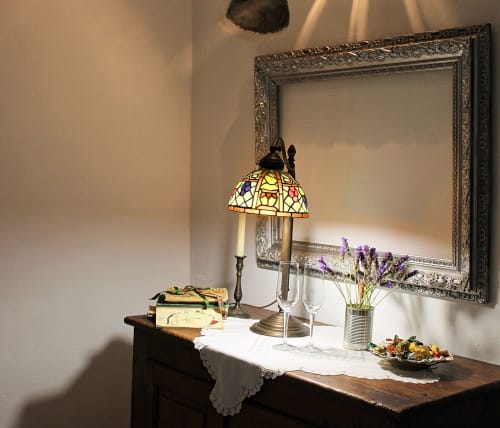 Élégant espace de travail à Agritusmo Stecadò avec lampe vitrail, fleurs, verres de vin et miroir dans l'Appartement Il Soppalco