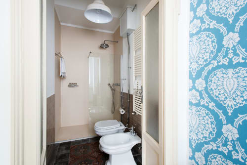 Bagno moderno dell'hotel Porta Tosa Milano con sanitari bianchi, doccia, scaldasalviette e damasco blu decorativo