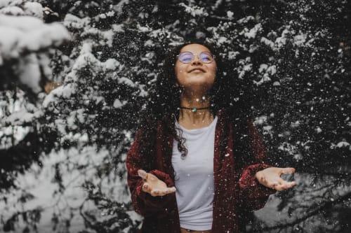 Woman enjoying snowfall among frosted trees in Grignan, France near Le Pavillon M boutique hotel and spa