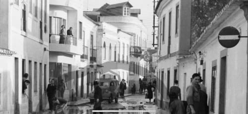 Rua de paralelepípedos históricos em Coruche, Portugal com casarões brancos e veículo vintage na pousada Patio Da Villa
